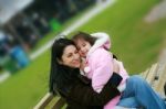 Mom And Daughter Sitting On Bench Stock Photo