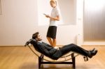 Woman Reading Man Lying On Chaise Longue Stock Photo