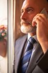 Middle-aged Businessman Listening On Smartphone At Home Stock Photo