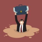 Businessman With Briefcase Full Of Money Sinking In A Quicksand Stock Photo