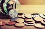 Coins Spilling Out Of A Glass Bottle Stock Photo