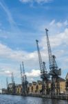 Old Dockside Cranes Alongside A Waterfront Development Stock Photo