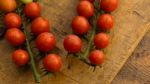 Cherry Tomatoes On Display On Wooden Chopping Board And Wooden Table Stock Photo