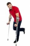 Young Man Walking With Crutches Stock Photo