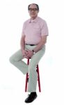 Confident Old Man Resting On Stool Stock Photo