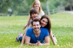 Happy Young Family Lying On Grass Stock Photo