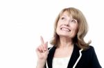 Smiling Woman Pointing Upwards Stock Photo