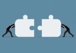 Businessmen Pushing Two Jigsaw Pieces Together Stock Photo