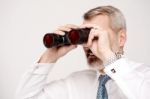 Male Execuitve Peers Through Binoculars Stock Photo