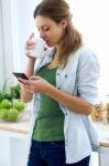 Beautiful Young Woman Using Her Mobile Phone And Enjoying Breakf Stock Photo