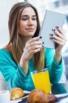 Pretty Woman Using Tablet While Having Breakfast In Coffee Shop Stock Photo