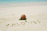 Maldives Written In A Sandy Tropical Beach And Coconut Fruit Stock Photo