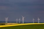 Green And Yellow Fields With Wind Turbines Generating Electricit Stock Photo