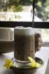 Hand On Iced Coffee At Balcony Wooden Table Stock Photo