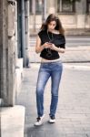 Woman Listens Music And Walks On The Street Stock Photo