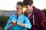 Portrait Of Young Couple Using They Smartwatch After Running Stock Photo