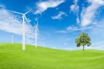 Wind Turbine And Tree On Green Grass With Blue Sky Background Stock Photo