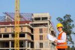 The Young Engineer Holds The Blueprint Over Building Being Built Stock Photo