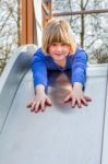 Young Girl Lies Forward On Slide Stock Photo