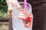 Hand On Serving Glass Of Iced Strawberry Soda Drink Stock Photo