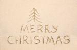 Merry Christmas Inscription On Wet Yellow Beach Sand Stock Photo