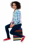 Cute School Girl Sitting On Stack Of Books Stock Photo