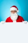 Aged Santa Standing Behind A Blank Ad Board Stock Photo