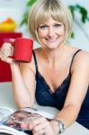 Attractive Woman Enjoying Coffee And Reading Magazine Stock Photo