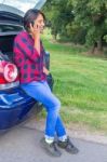 Woman Phoning Mobile Sitting In Car Trunk Outside Stock Photo