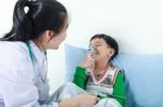 Asian Boy Having Respiratory Illness Helped By Health Professional With Inhaler Stock Photo