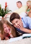 Two Young Kids Lying With A Book In Living Room Stock Photo