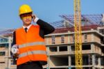 Young Engineer In Orange Shirt Stands Holding A Blueprint And Ta Stock Photo