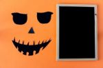 Halloween Concept With Chalkboard And Black Eyes And Mouth On Orange Background Stock Photo