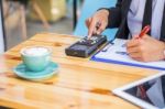 Business Man Sitting On A Calculator To Figure Out In A Coffee S Stock Photo