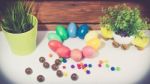 A Few Colorful Easter Eggs As A Flower Shape With Candies And Chocolate Trails And Garden Plants Over Wood Background Straight View Happy Easter Stock Photo