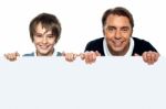 Father And Son Posing Behind Big Blank Banner Ad Stock Photo