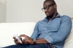 Handsome Young Man Using His Mobile Phone At Home Stock Photo