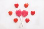 Pink Valentine's Day Heart Shape Lollipop With Small Red Candy In Cute Pattern On Empty White Paper Background. Love Concept. Colorful Hipster Style. Knolling Top View Stock Photo