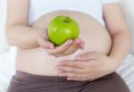 Pregnant Belly With Green Apple Stock Photo