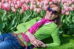 Woman Lying In Front Of Pink Tulip Field Stock Photo