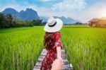 Woman Holding Man's Hand And Leading Him To Wooden Path And Green Rice Field In Vang Vieng, Laos Stock Photo