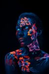 Beautiful Flowers In Uv Light On A Young Girl Face And Body Stock Photo