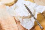 Camembert Cheese Wrapped In Paper With Vintage Knife On Wooden T Stock Photo