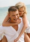 Couple Piggyback Ride At Beach Stock Photo