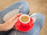 Woman In Torn Jeans Sitting At Coffee Shop Stock Photo