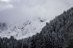 Snowy Mountain Range With Clouds And A Forest Stock Photo