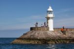 Brixham, Devon/uk - July 28 : People Fishing Near The Lighthouse Stock Photo