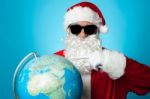 Santa Pointing At Globe Map Stock Photo