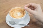 Hand On Hot Cup Of Coffee Latte Stock Photo