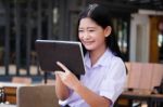 Portrait Of Thai High School Student Uniform Beautiful Girl Using Her Tablet Stock Photo